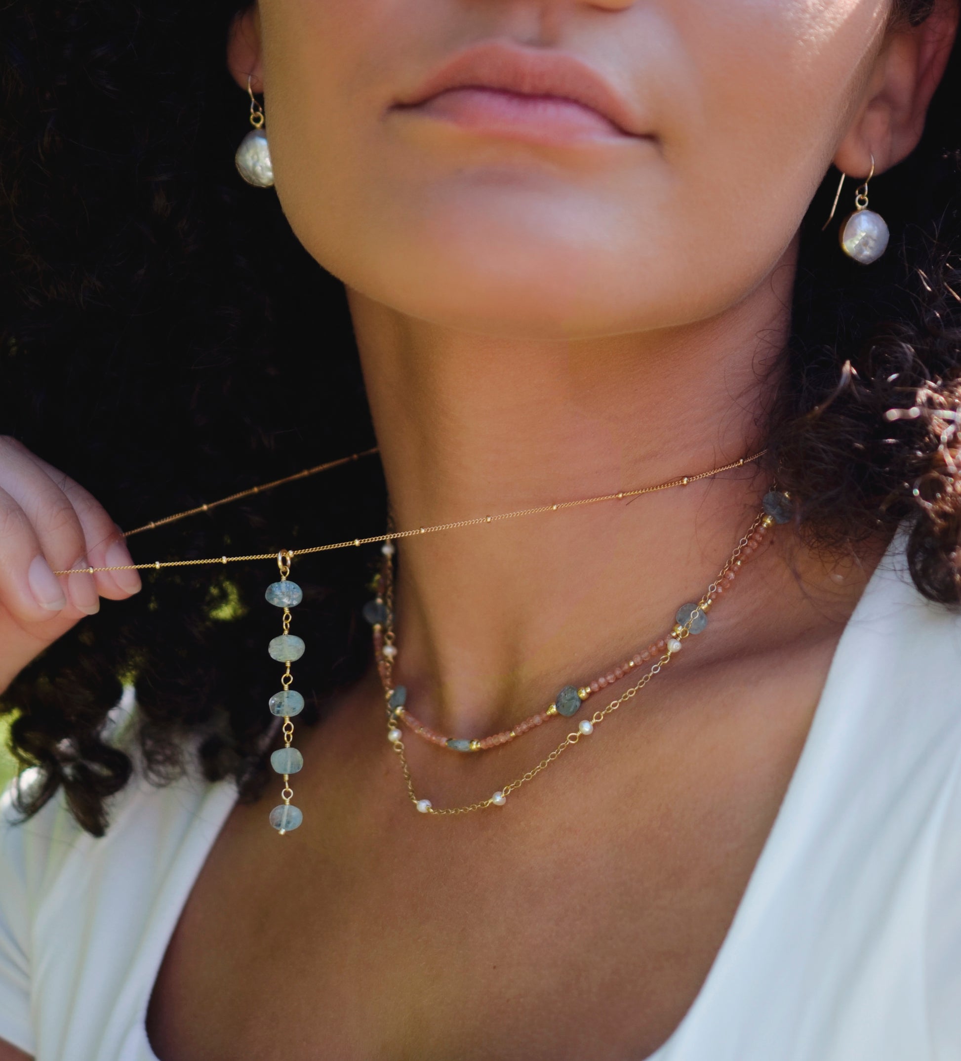 Genuine white freshwater pearls set onto a 14k gold filled chain. Modeled image, layered with other necklaces.