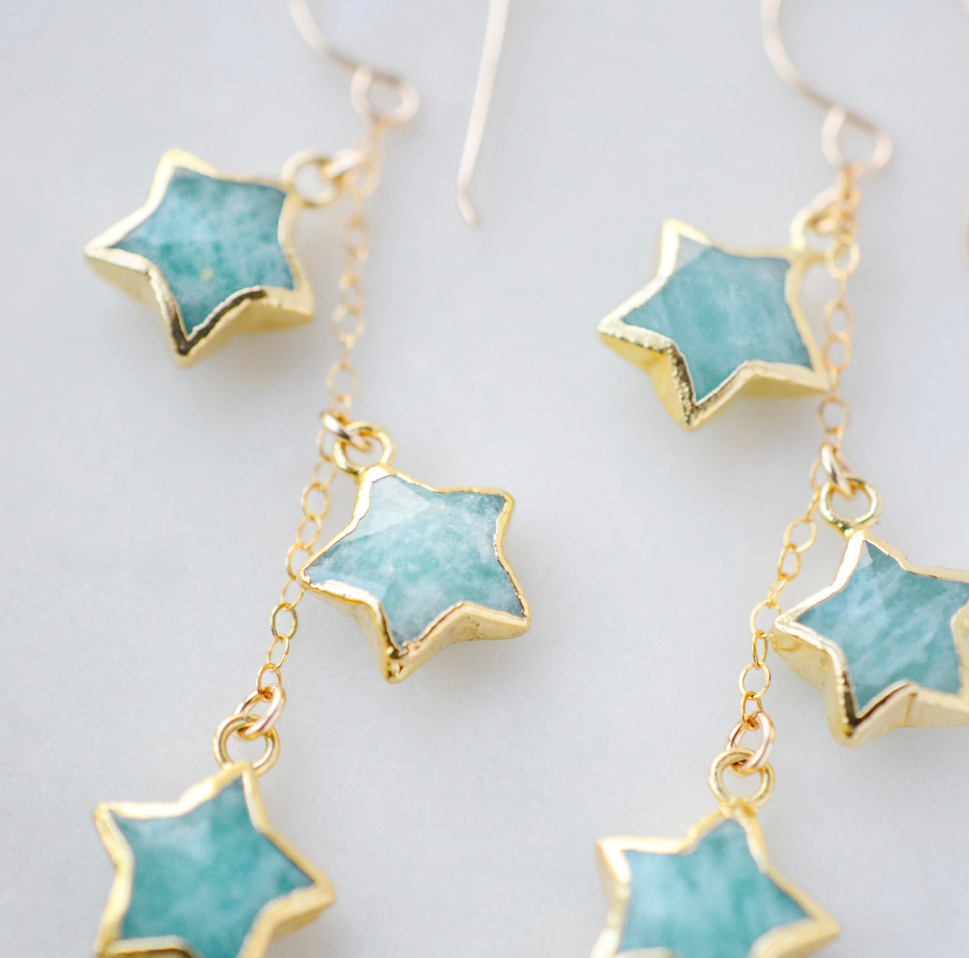 Amazonite faceted gemstone stars suspended from a dainty gold chain. Close up image.