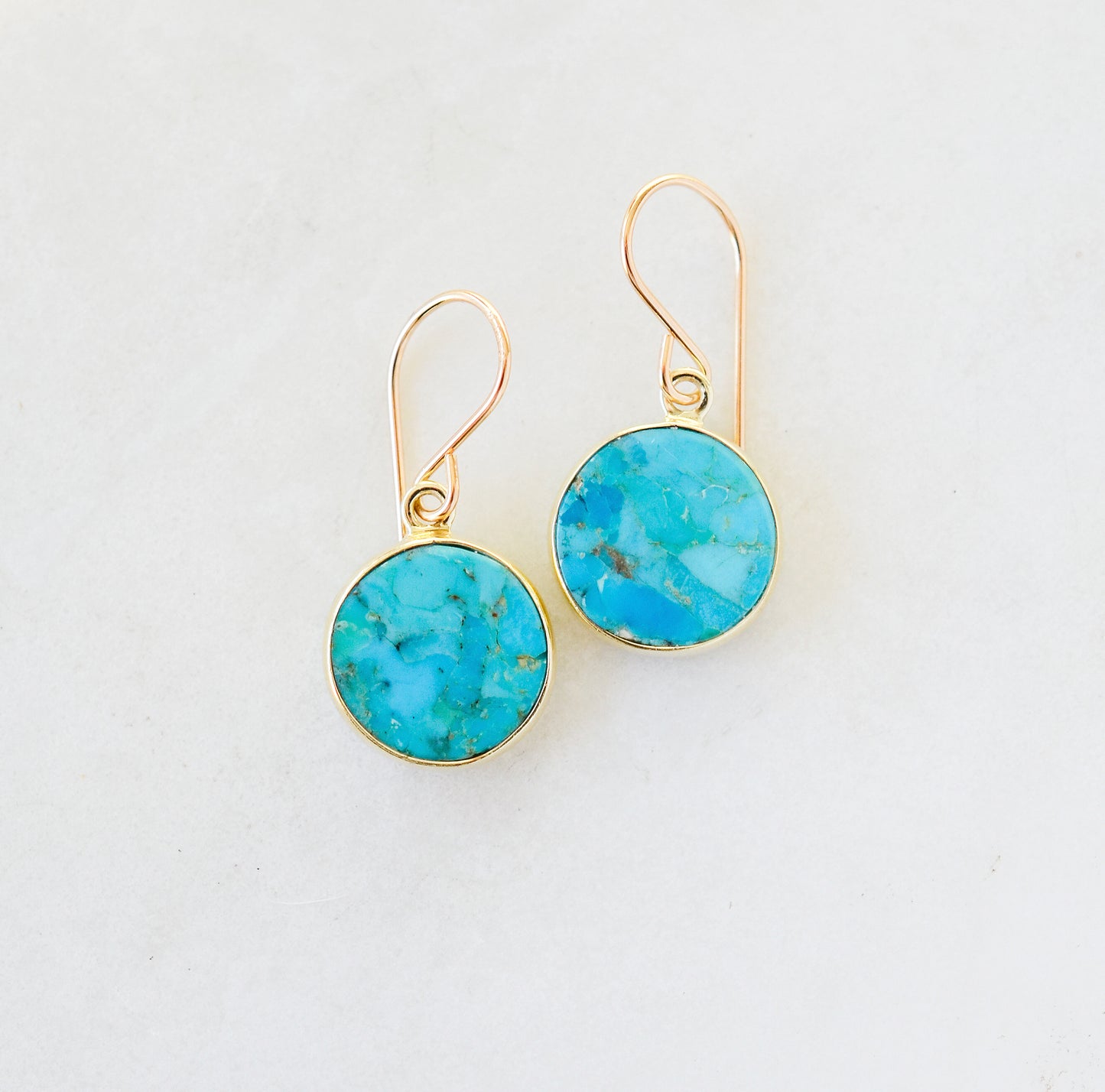 Real turquoise gemstones set in gold vermeil bezels and suspended from 14k gold filled ear wires. These handmade earrings feature smooth polished round stones. Artisan jewelry from Connecticut by GEMNIA.