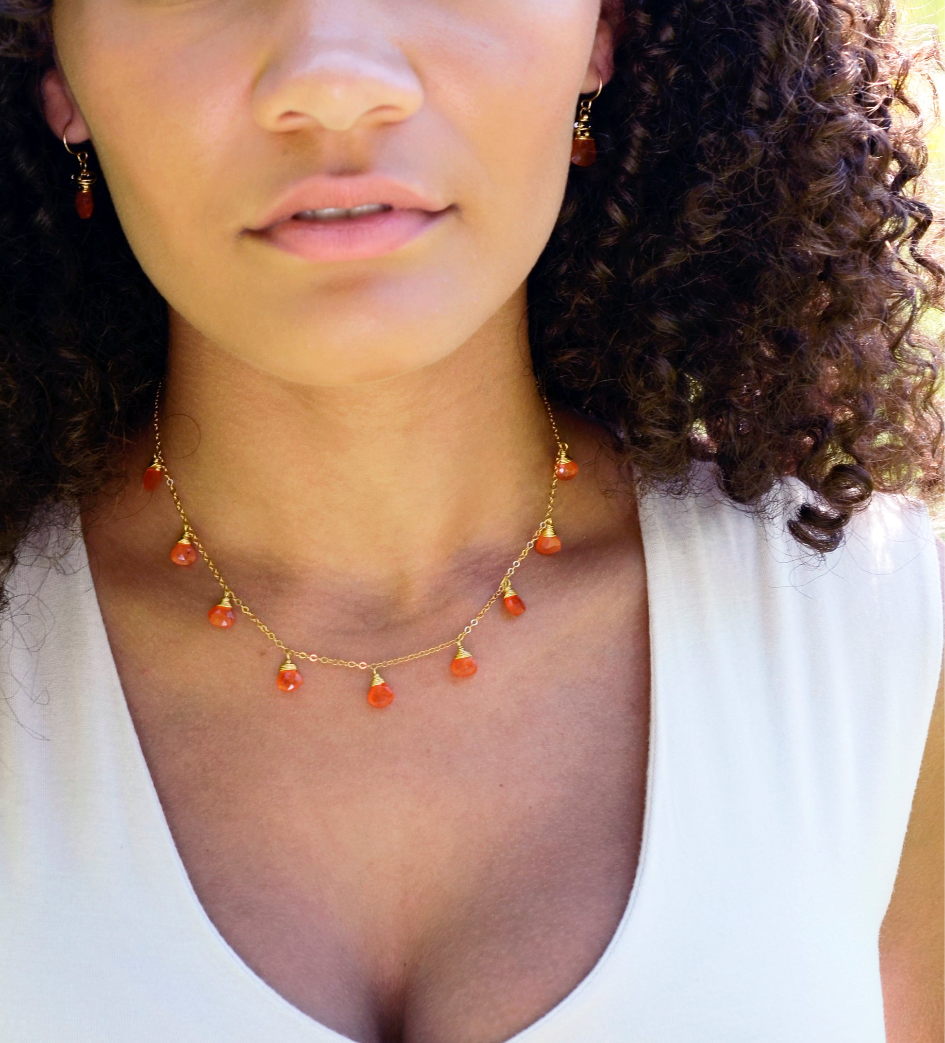 Handmade necklace featuring nine natural Carnelian gemstones set onto a gold filled chain. Sterling Silver is also available. Modeled Image.