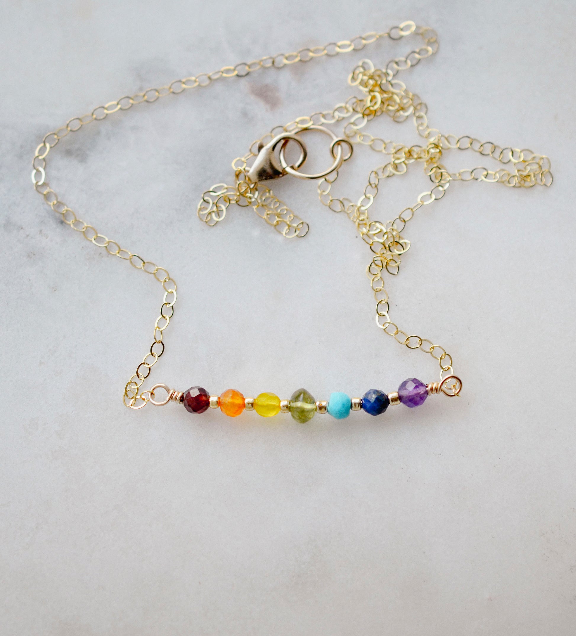 Gemstone bar necklace shown in 14k gold filled. The stones are arranged in the colors or the rainbow or chakras.