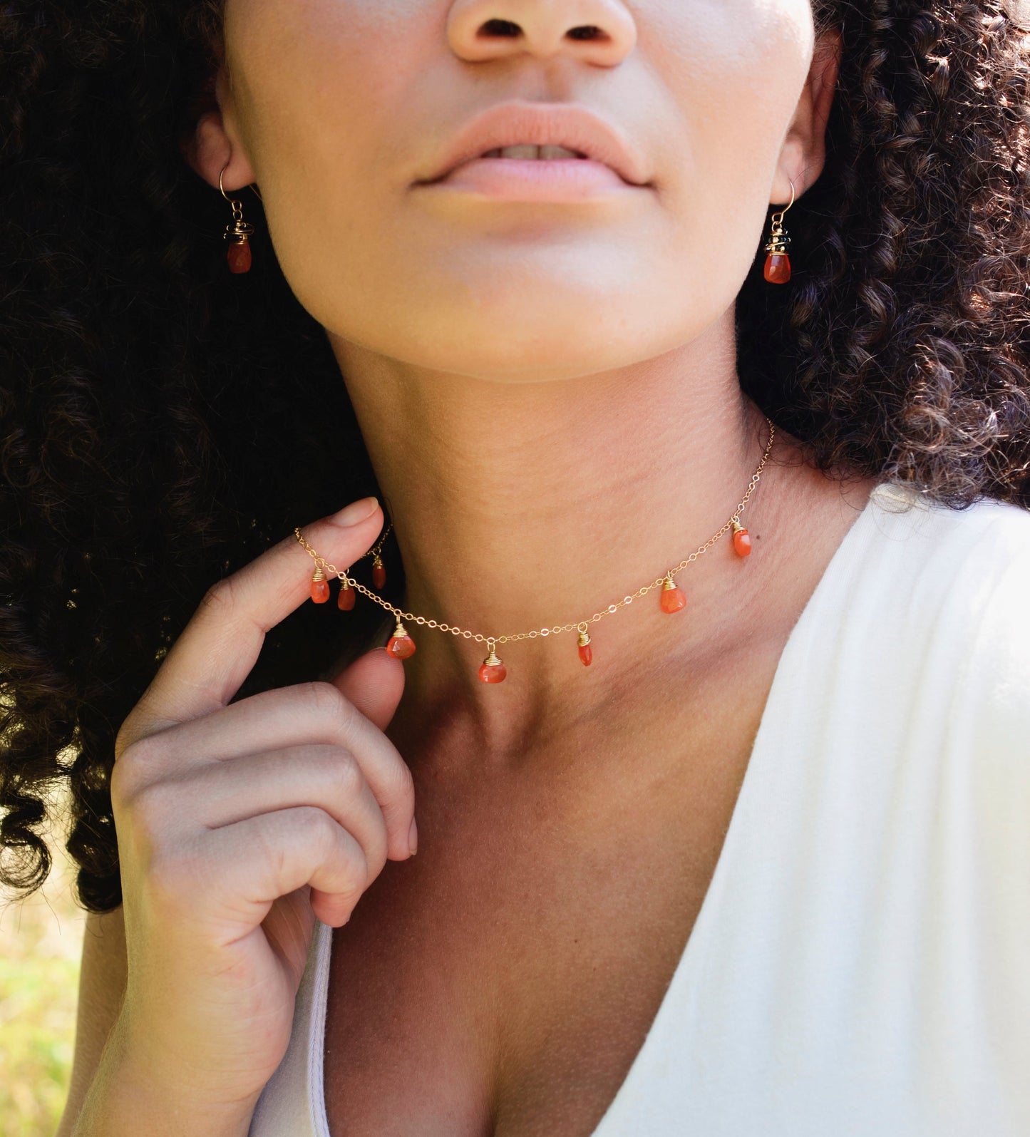 Multiple carnelian teardrop gemstones hang from a 14k gold filled chain. Modeled image. 