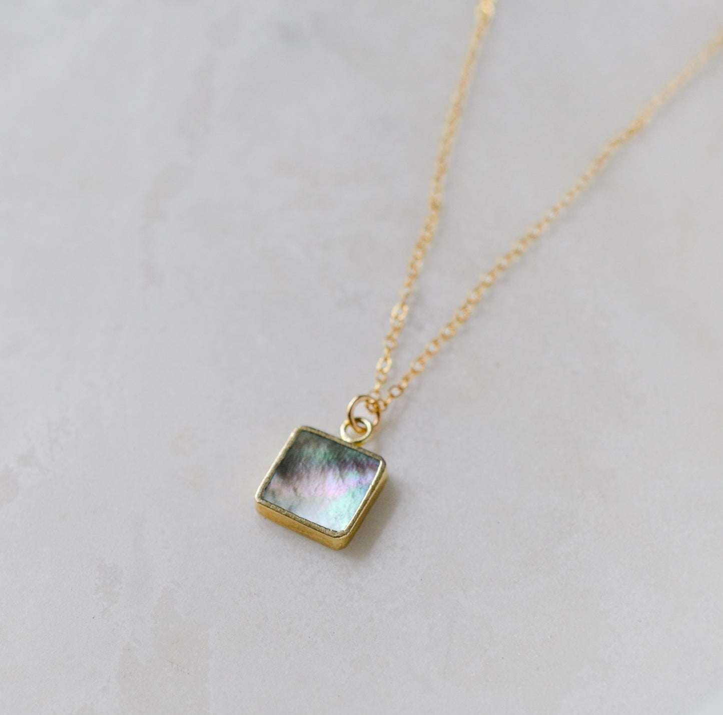 A genuine natural iridescent mother of pearl square shaped pendant set on a 14k gold filled chain. This delicate necklace is handmade in Connecticut by Gemnia.