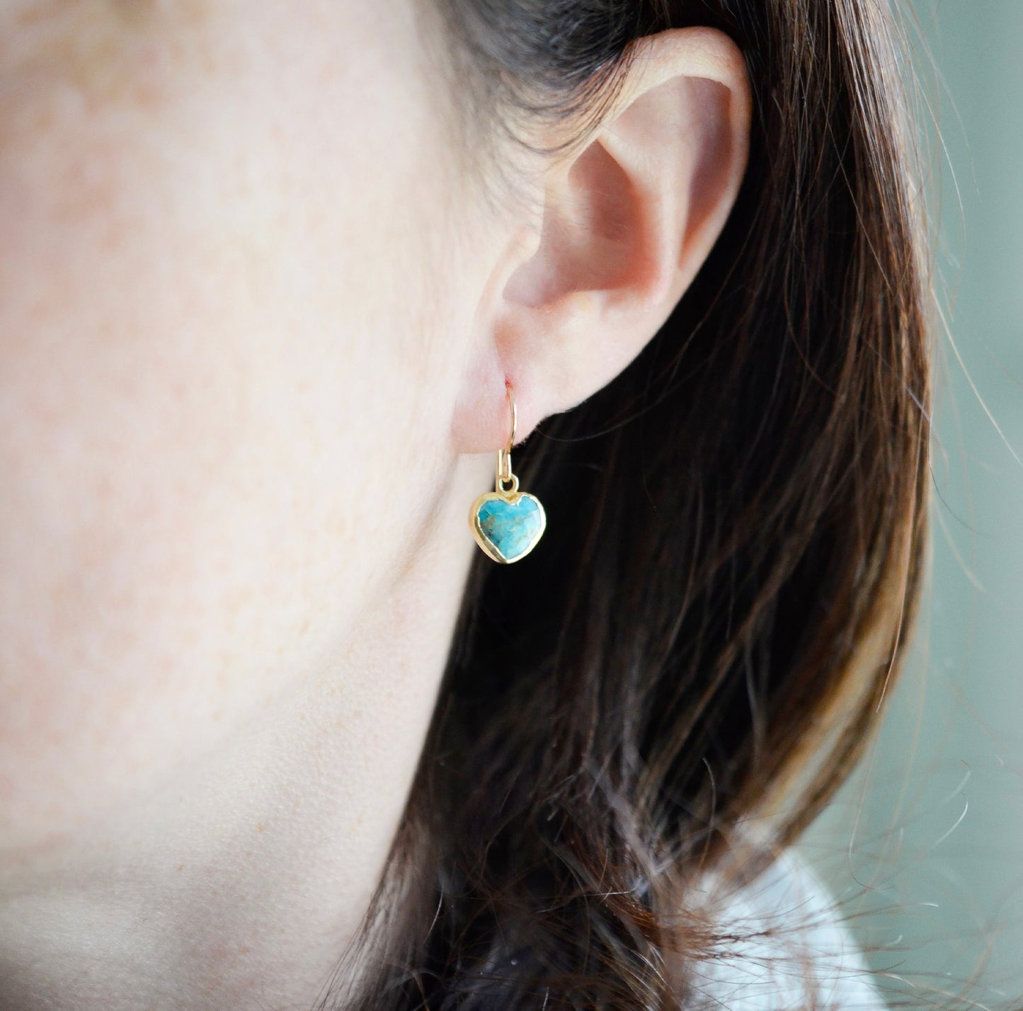 Genuine, natural blue turquoise faceted hearts set on 14k gold filled earring hooks. The stones range in blue and green, with some containing white or brown.