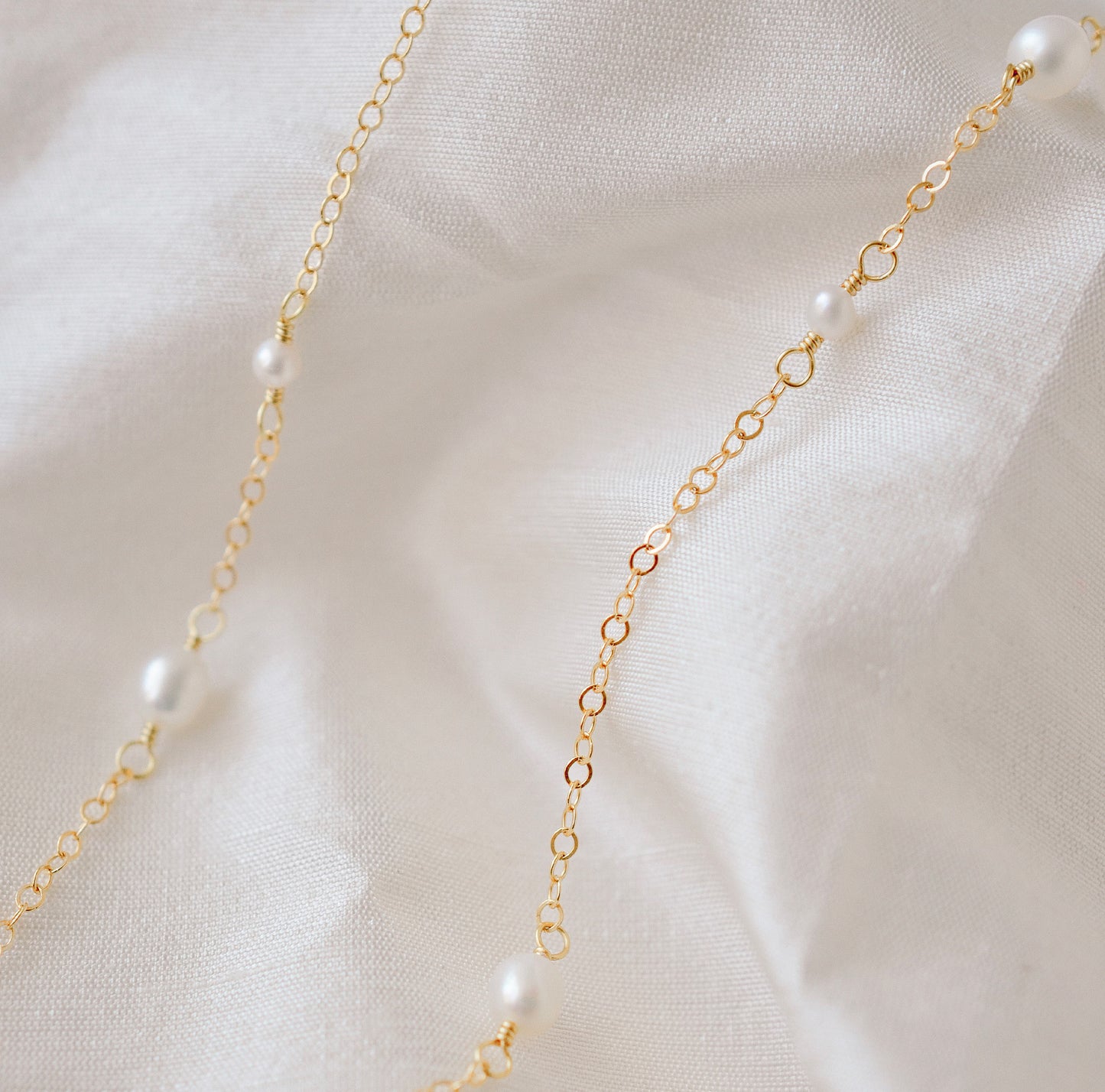 Genuine white freshwater pearls of varying sizes alter on this chain necklace. The gold style is shown.