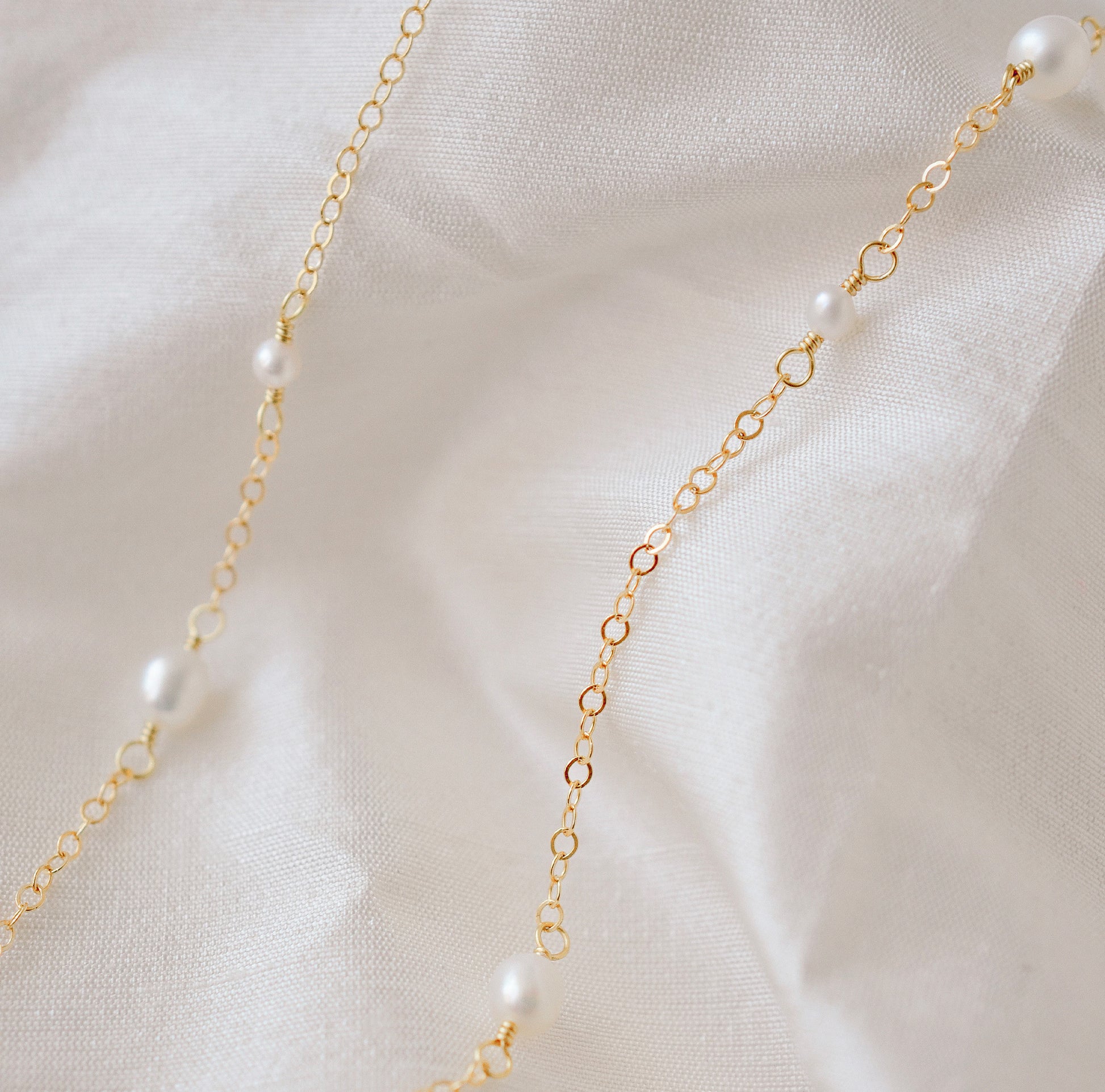 Genuine white freshwater pearls of varying sizes alter on this chain necklace. The gold style is shown.