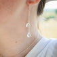 Long clear crystal quartz earrings with two teardrop dangles hanging from a dainty chain. Modeled in sterling silver with the matching necklace.