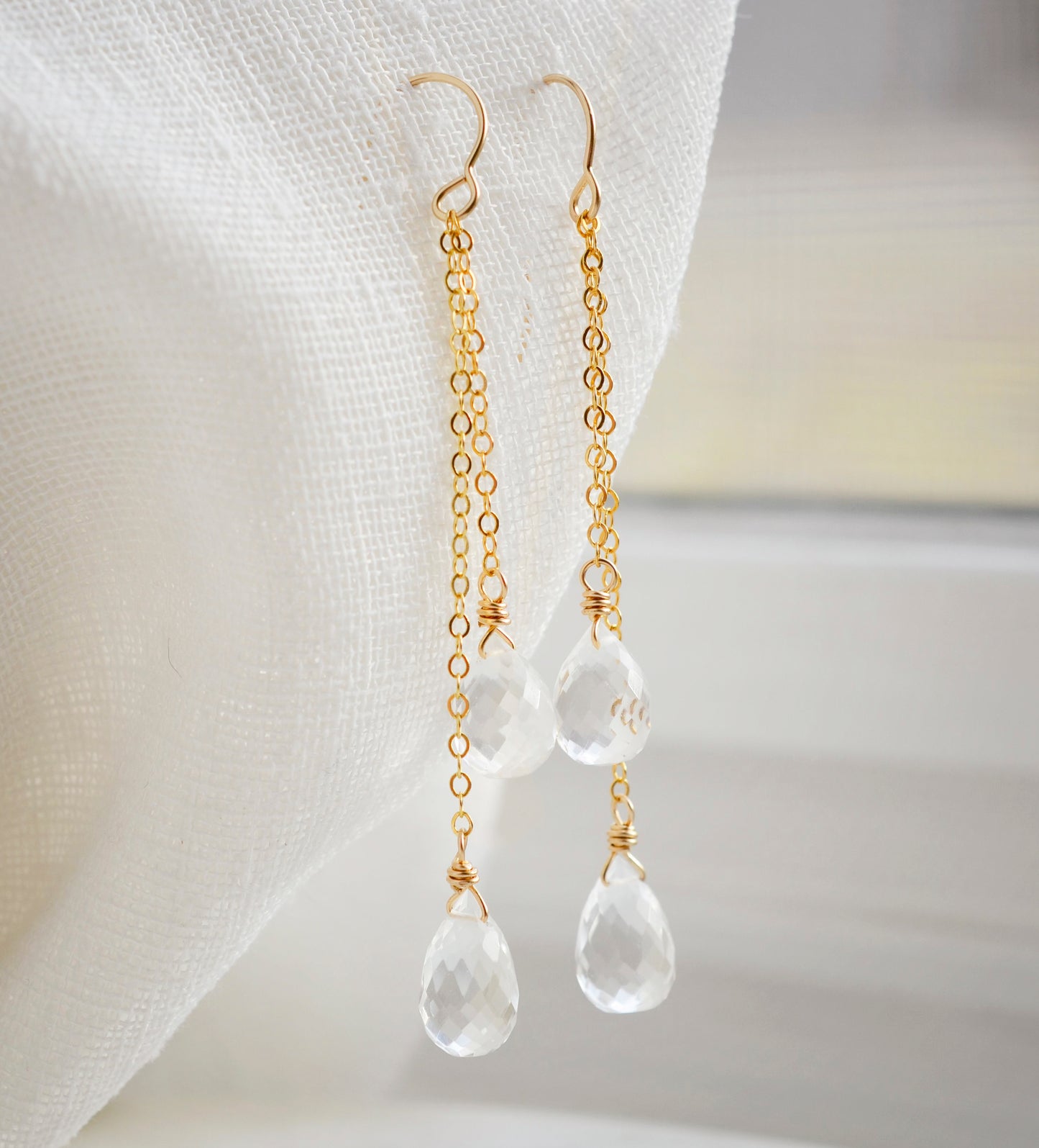 Long clear crystal quartz earrings with two teardrop dangles hanging from a dainty 14k gold filled chain.