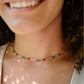 Tiny stones arranged in the order of the seven chakras or rainbow colors. Colors include: purple, blue, aqua, green, yellow, orange, and red. Modeled image. Handmade in Connecticut by Gemnia Jewelry.