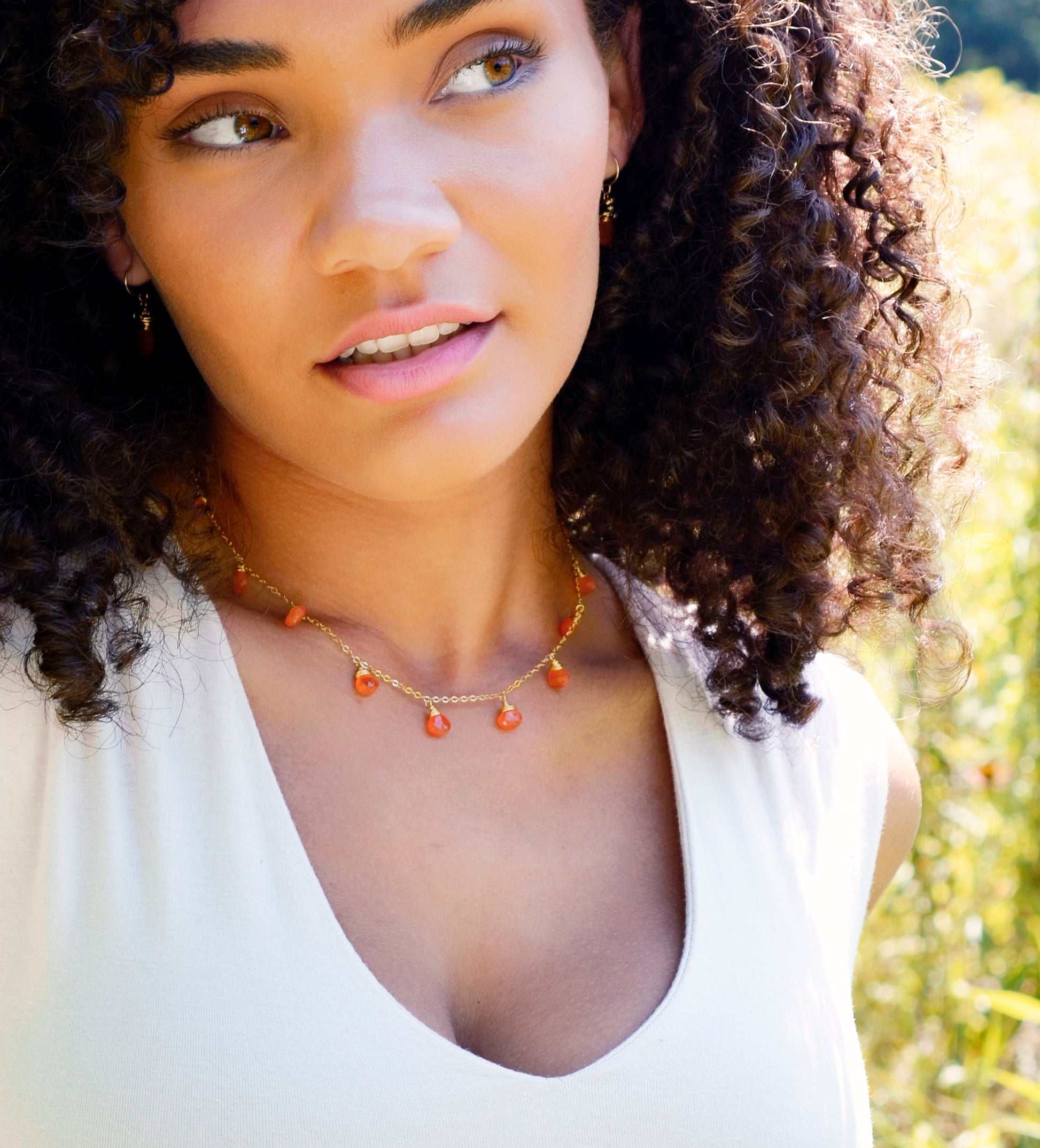 Handmade necklace featuring nine natural Carnelian gemstones set onto a gold filled chain. Sterling Silver is also available. Modeled Image.