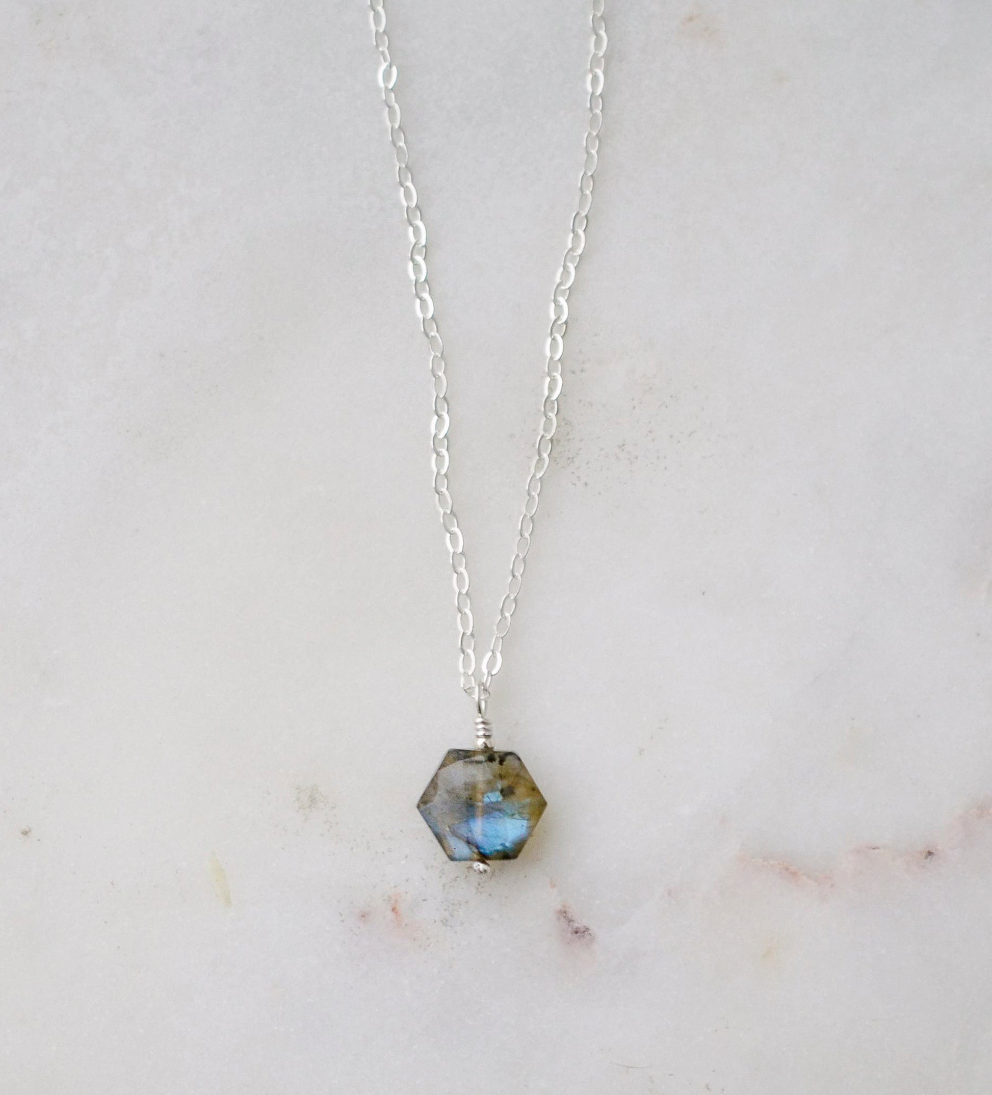 Blue - green natural labradorite gemstone in a hexagonal shape shown on a sterling silver chain.