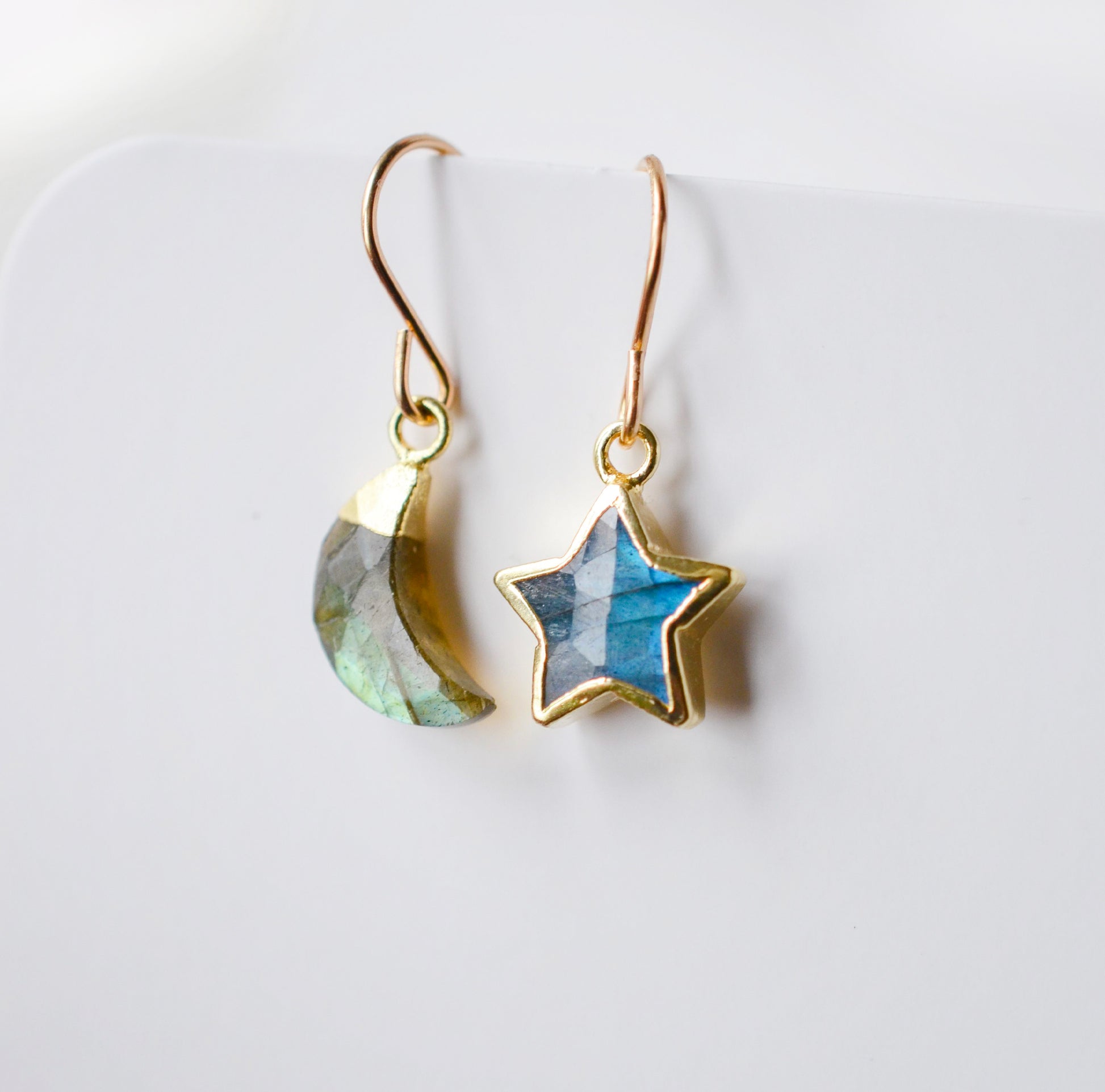 Labradorite Moon and Star earrings. One dangle is a faceted crescent moon, while the other is a star. The stones are naturally gray in color, but shift blue or green with movement. Available in gold or silver.