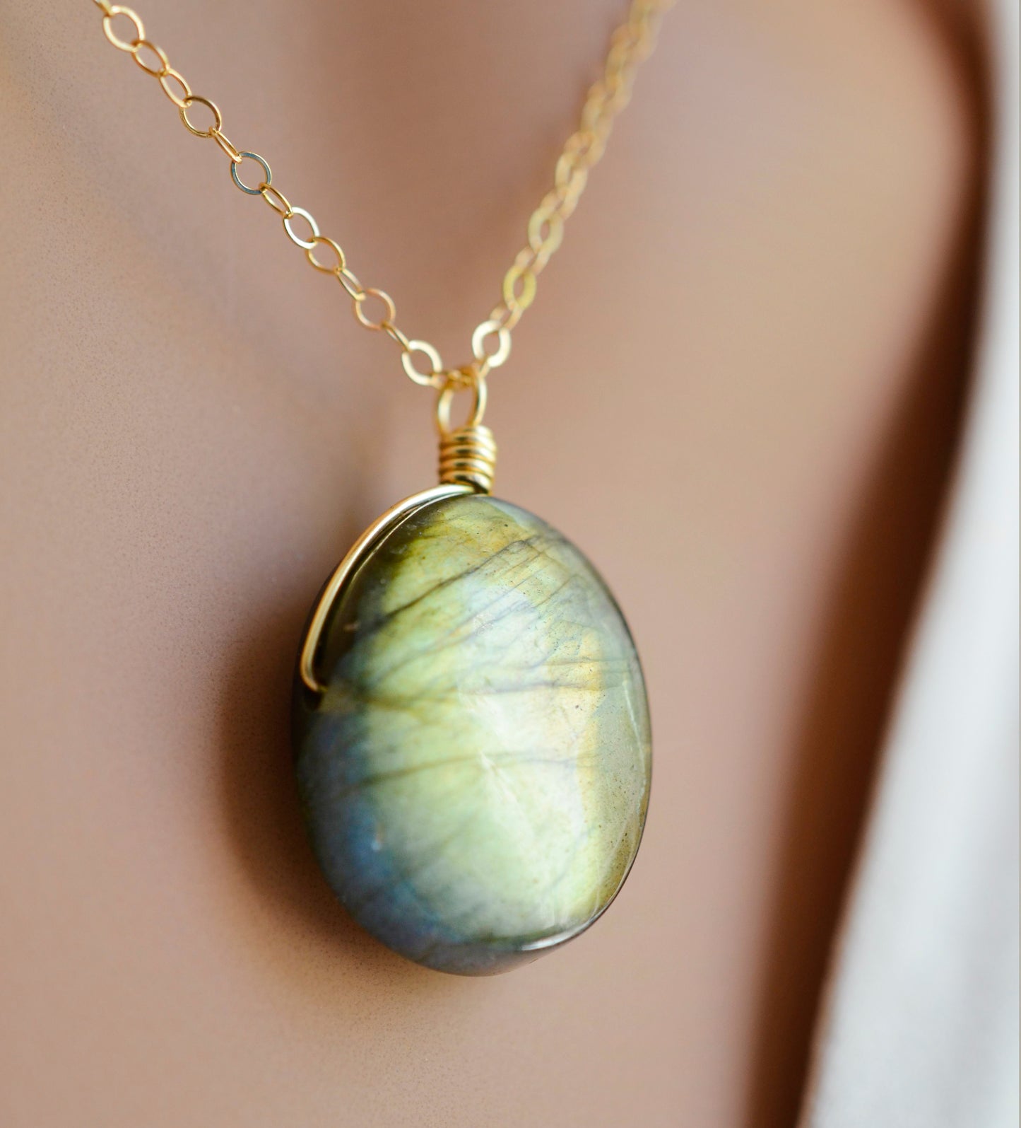 Labradorite oval pendant with yellow-green flash. The chain in 14k gold filled. Close up image.