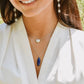A modeled image of a woman wearing two layered necklaces. One is a white freshwater pearl. The other is a real blue lapis lazuli faceted oval stone pendant. Shown in sterling silver. This jewelry is handmade by Gemnia.