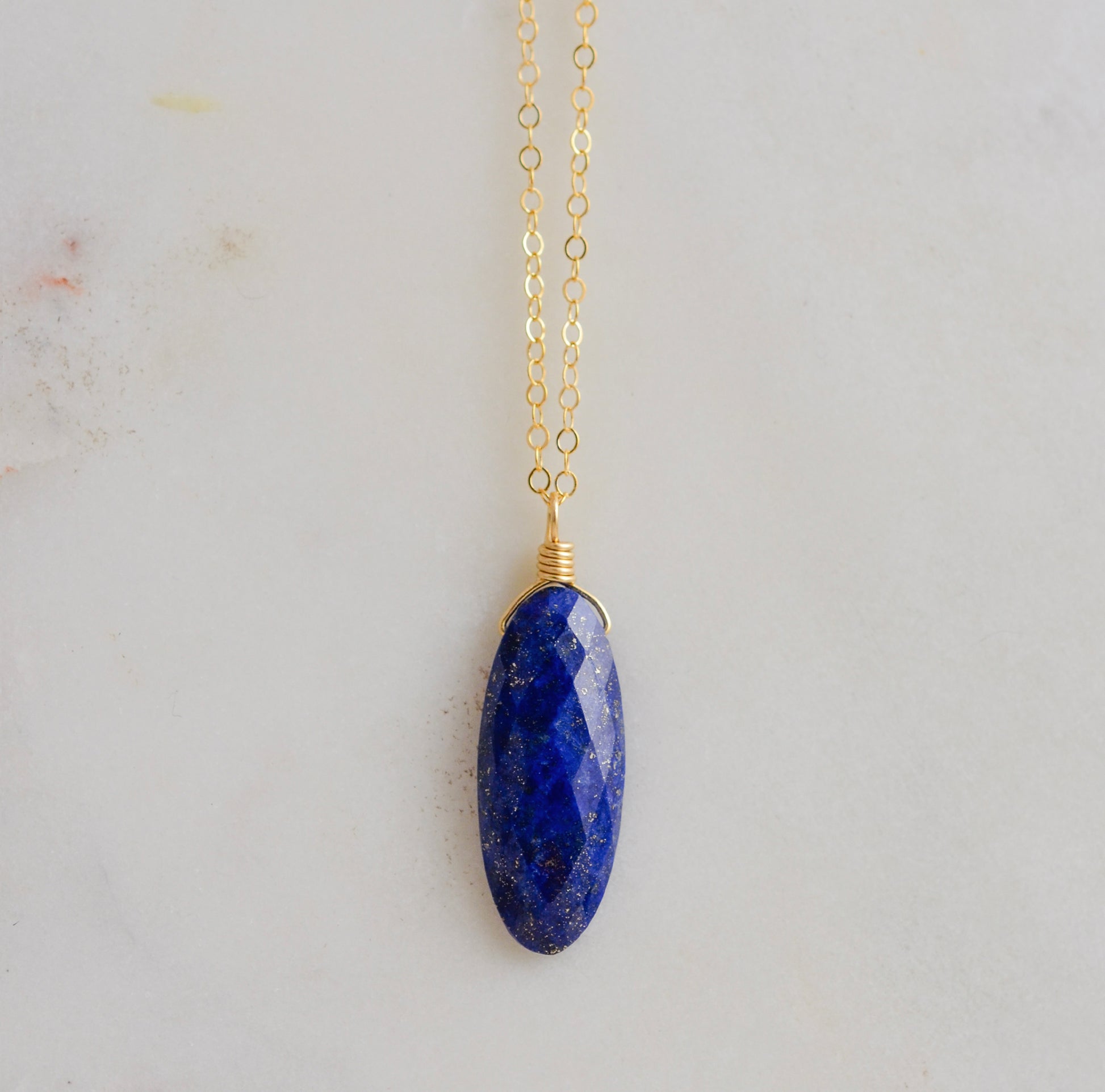 A handmade natural genuine blue lapis lazuli gemstone pendant on a dainty 14k gold filled chain. This necklace is made in Connecticut by Gemnia Jewelry.
