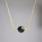 Close up of a natural black lava stone pendant on a gold filled chain. 