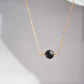 A round black lava stone suspended from a 14k gold filled chain.