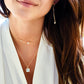 Close-up of a woman wearing layered gold gemstone and pearl necklaces and earrings. All jewelry is handmade in Connecticut USA by Gemnia.