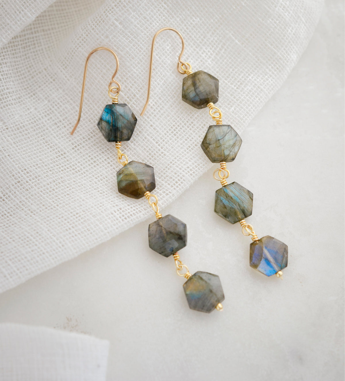 Long fancy labradorite earrings featuring four gemstone dangles in a long like. Each stone contains natural blue and green flash and is a hexagon shape. Dainty, minimalist jewelry handmade in New England by Gemnia.