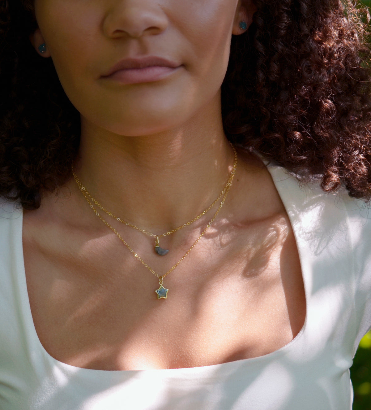 A dainty, gold, celestial style Labradorite star and moon necklace set layered on a model. This everyday jewelry is perfect for layering and stacking.