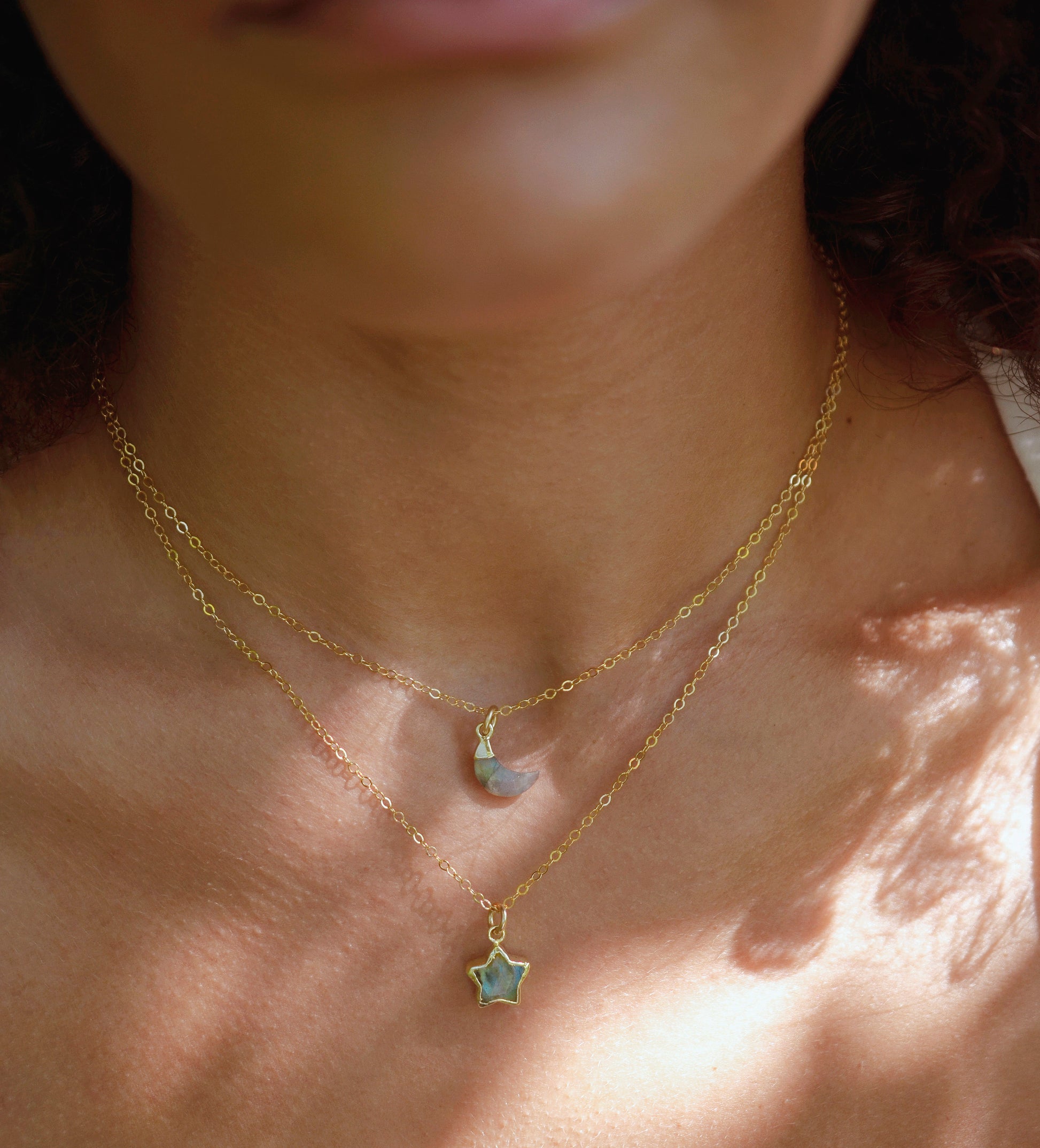 Labradorite star and moon pendants modeled in gold on a simple chain.