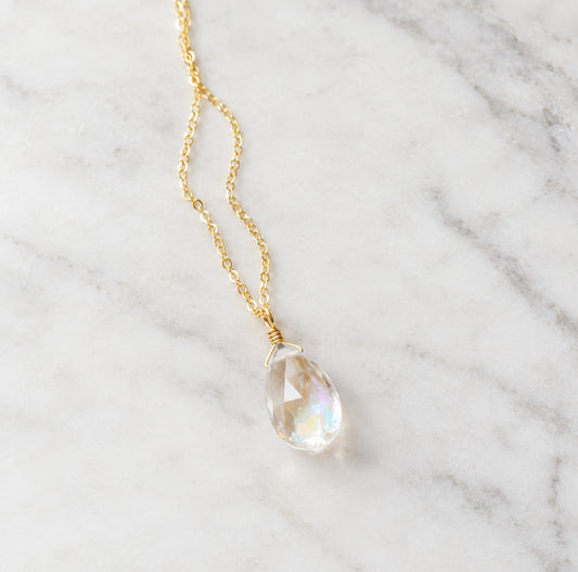 A faceted mystic topaz gemstone set on a dainty 14k gold filled chain. The stone is clear, but shimmers rainbow colors when turned from side to size. This pendant is handmade in Connecticut by Gemnia.