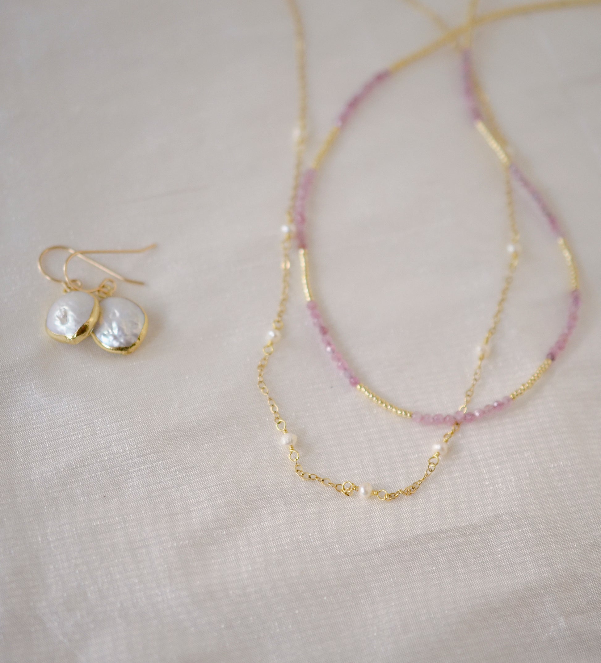 Genuine white freshwater pearls set onto a 14k gold filled chain. Shown with matching pearl earrings and a pick tourmaline necklace.
