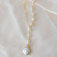 White freshwater pearl necklace with a large coin pearl pendant. Pearls fill one side of the necklace, while the other side is a dainty gold chain.