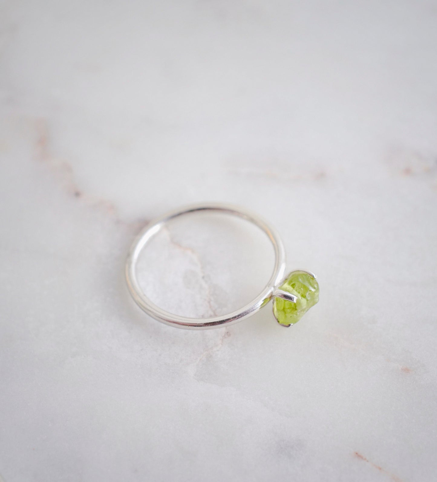 Rough green peridot ring on a sterling silver band. Close up image.