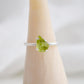 Dainty irregular shaped green peridot ring on a sterling silver band. Close up image.