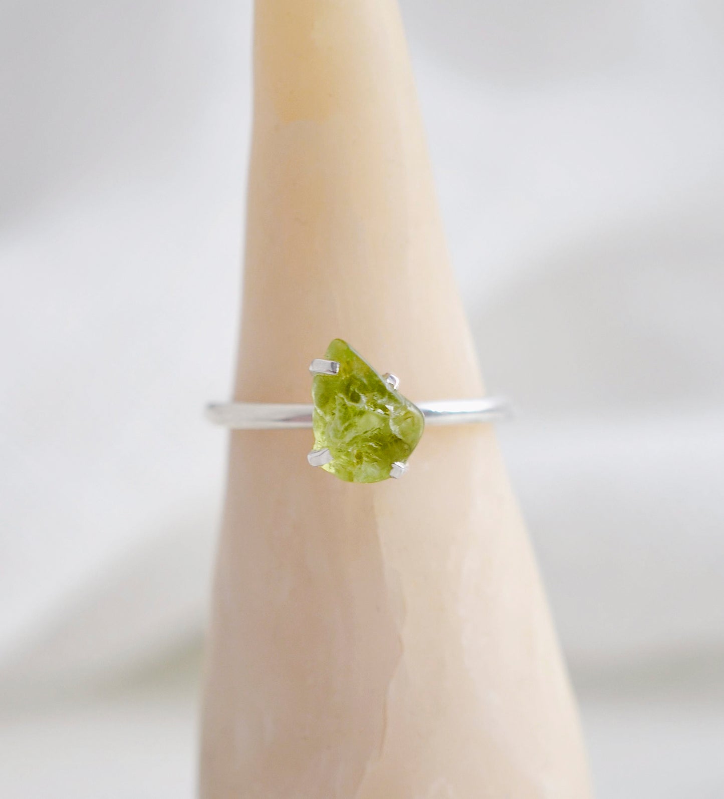 Dainty irregular shaped green peridot ring on a sterling silver band. Close up image.