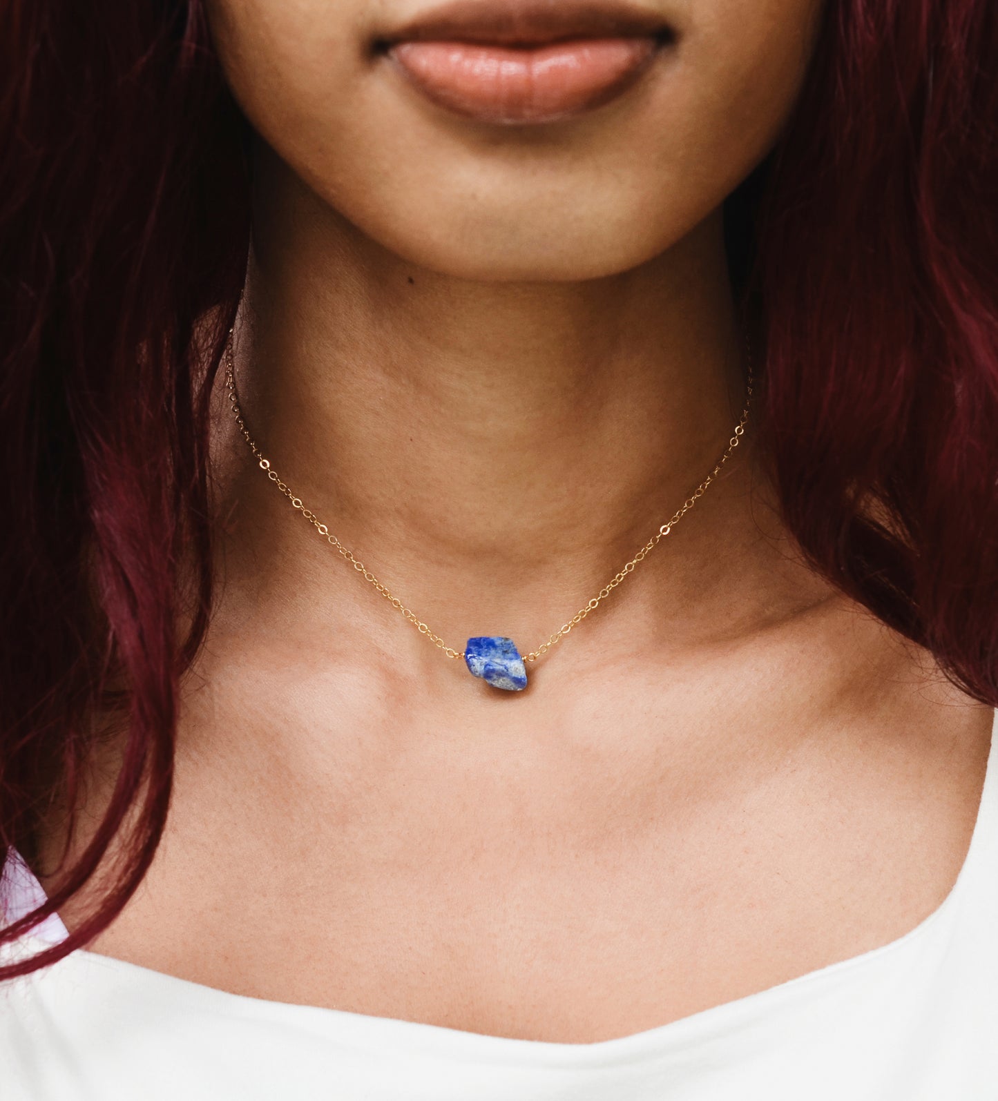 Raw blue lapis lazuli stone suspended from a gold chain. Modeled Image.