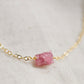 A close up of a minimalist pink tourmaline crystal set onto a 14k gold filled chain. 