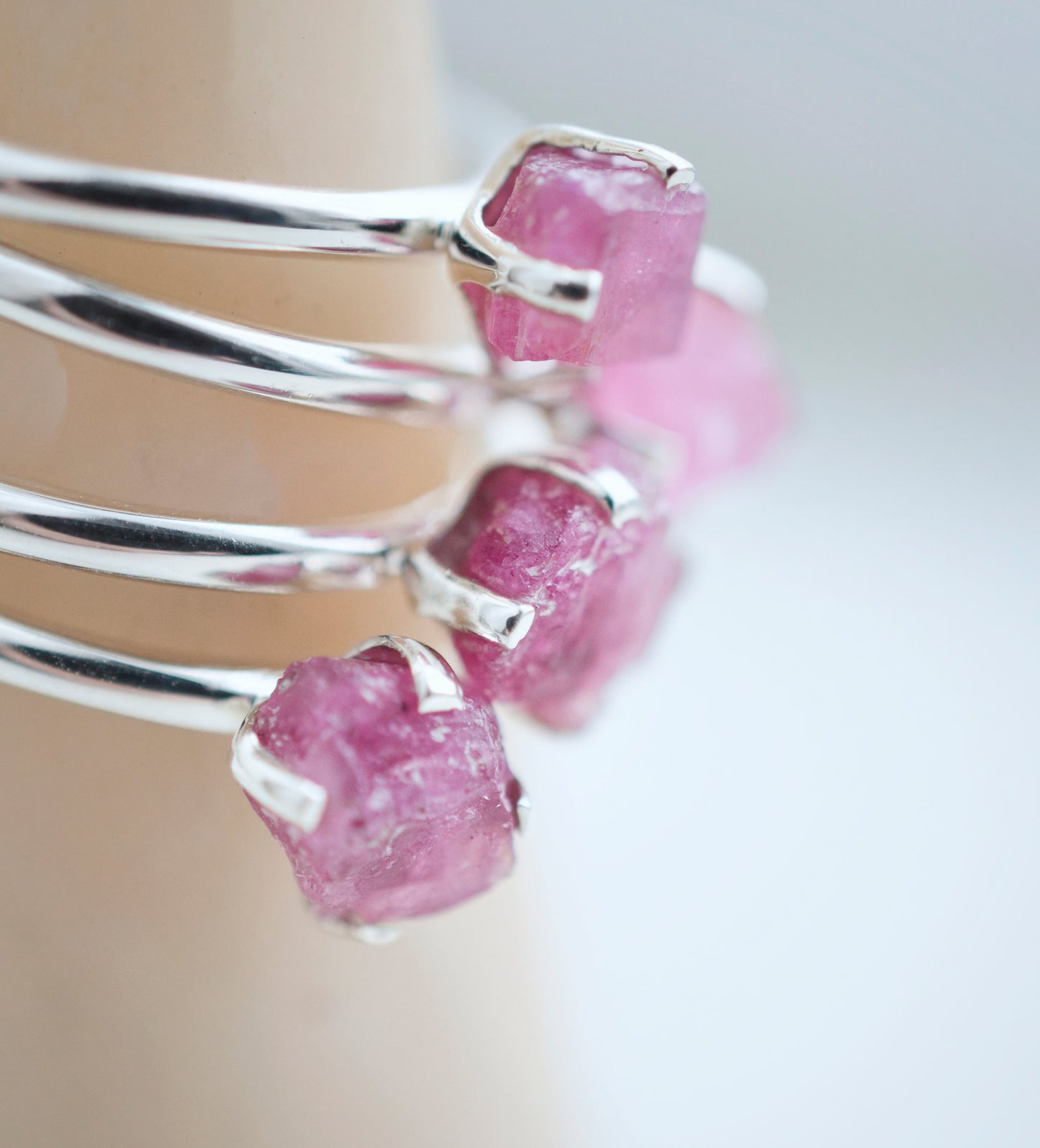 Close up of multiple rings with rough Pink Tourmaline gemstones set in sterling silver.