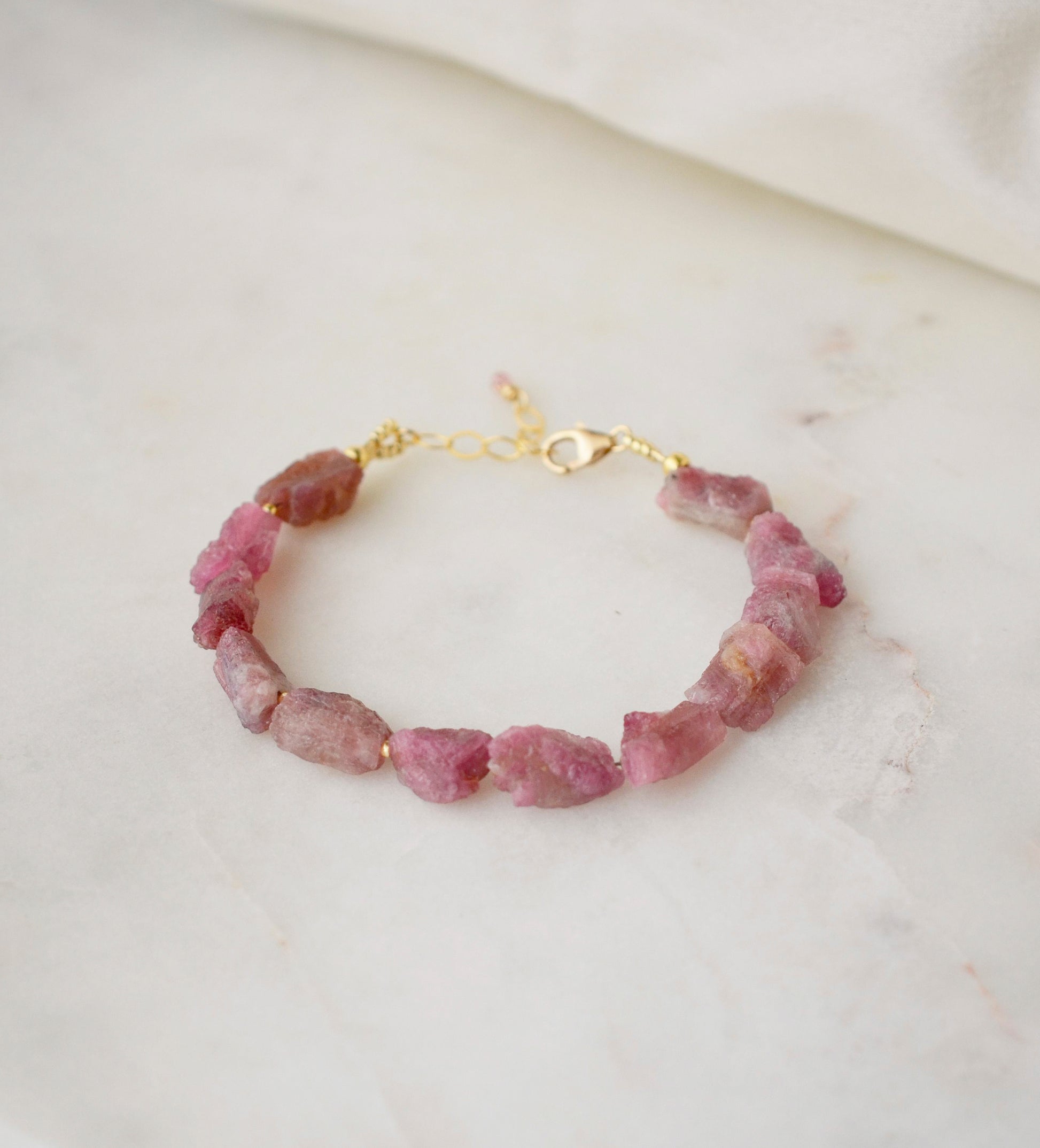 Raw pink tourmaline bracelet with tiny gold beads in-between each stone. The adjustable style is shown.