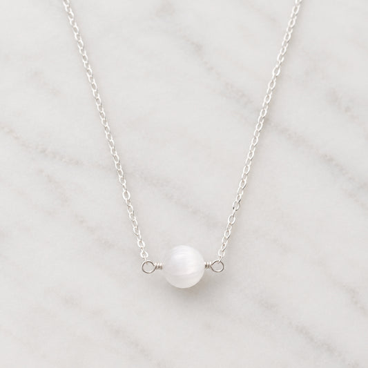 A genuine white selenite round stone set on a sterling silver chain. The crystal is smooth polished and handmade by Gemnia in New England.