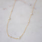 Natural white freshwater pearls of varying sizes on a dainty chain necklace. The gold style is shown.