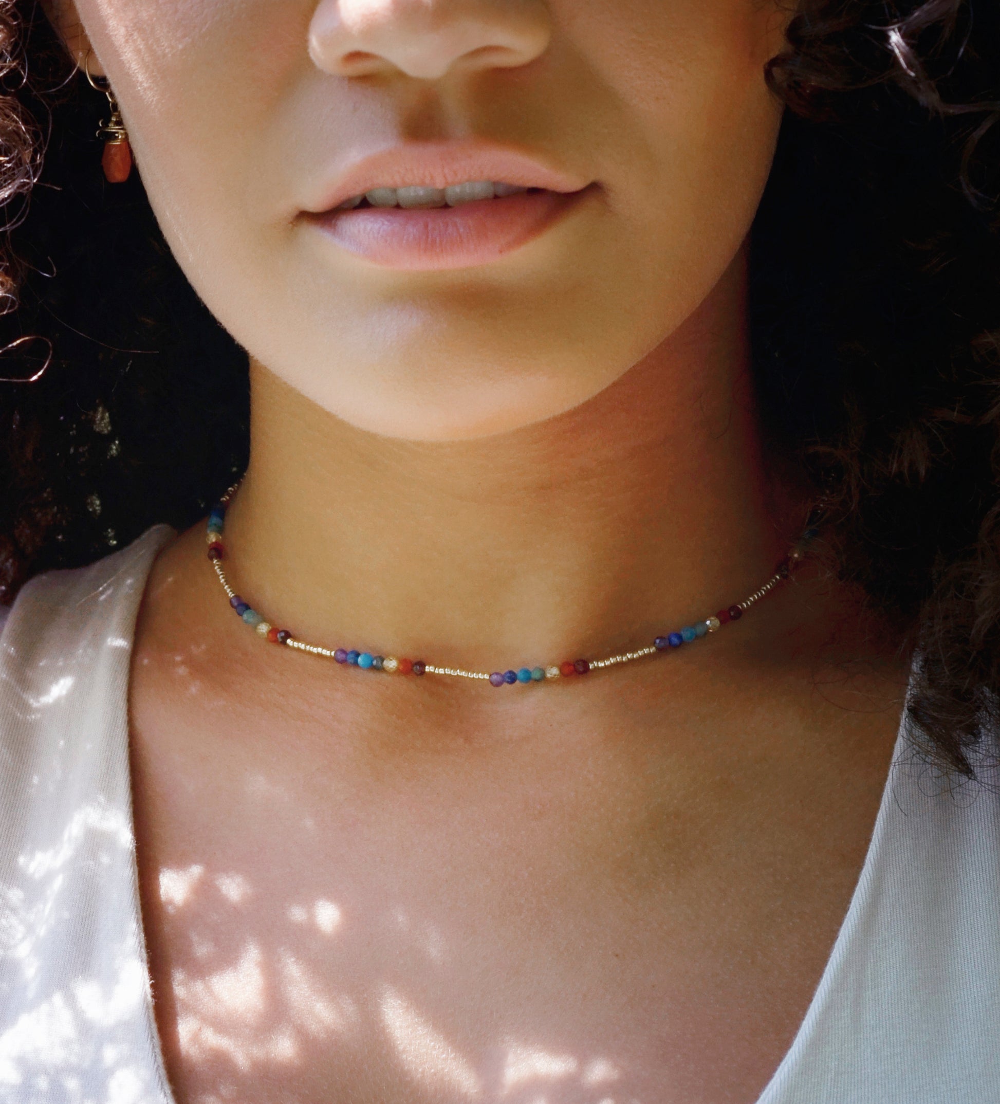 Tiny stones arranged in the order of the seven chakras or rainbow colors. Colors include: purple, blue, aqua, green, yellow, orange, and red. Modeled image.