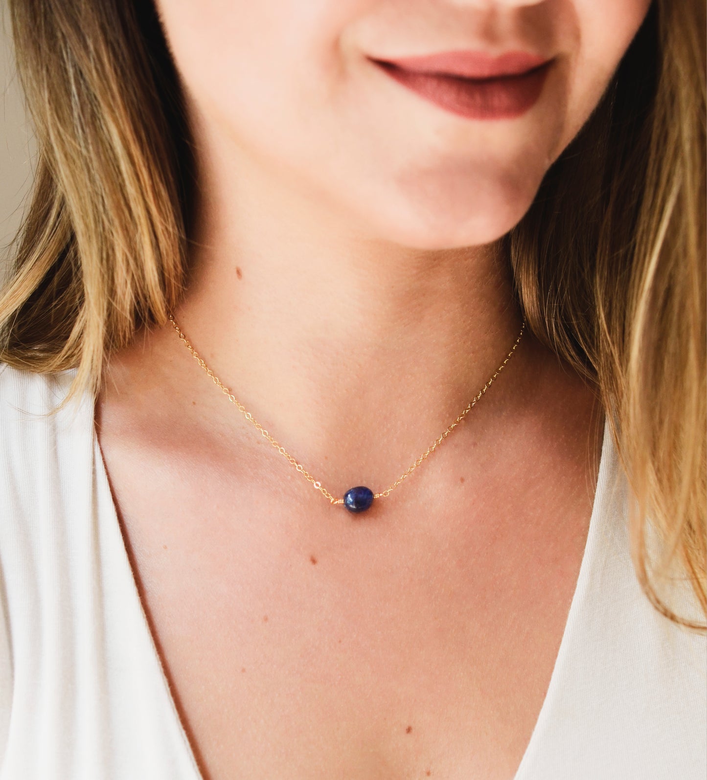 Small blue sapphire stone set onto a gold chain. The stone is a puffed oval shape. Modeled image.