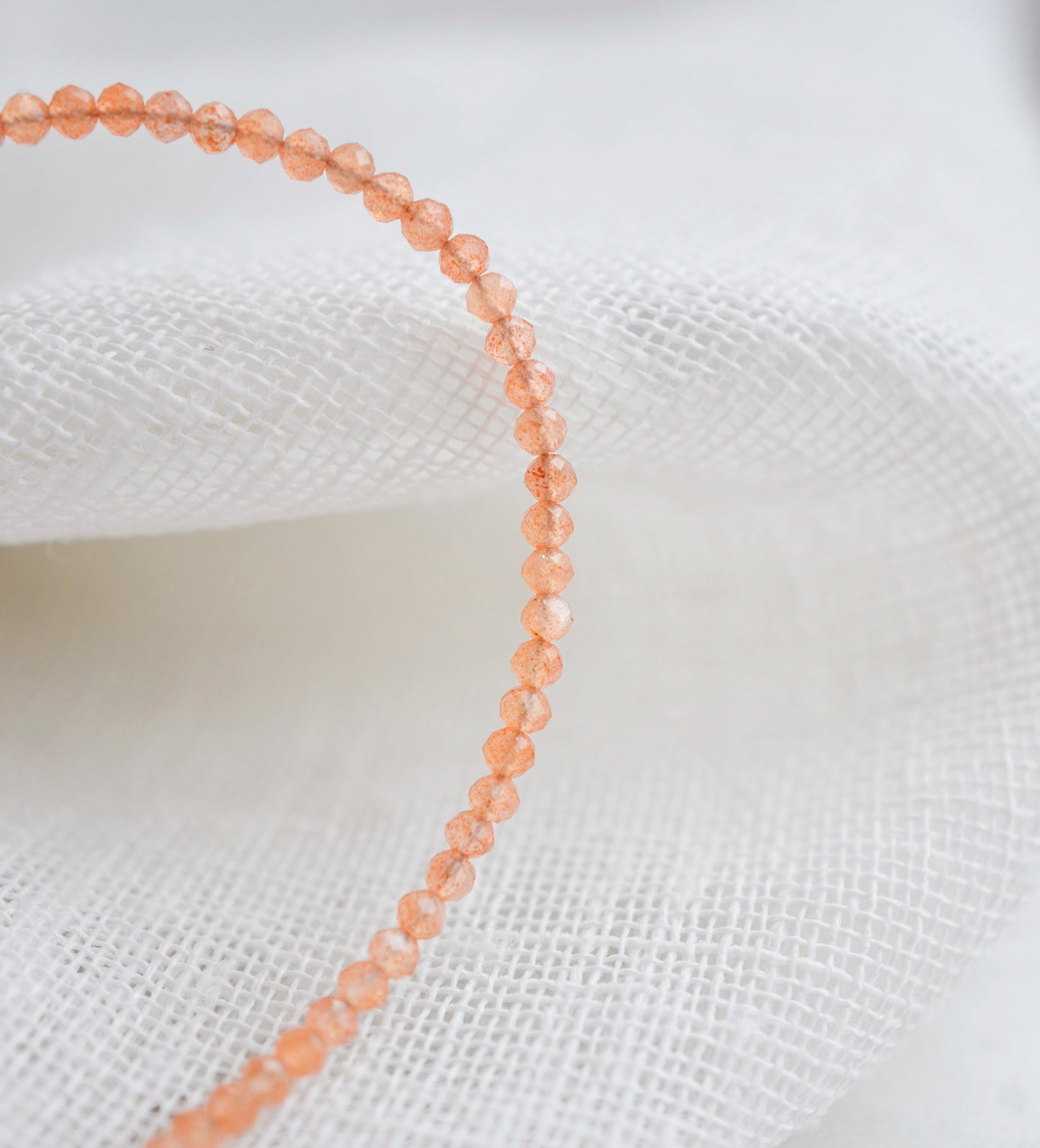 Genuine orange Sunstone beaded bracelet. The stones are round and faceted. Close up image.