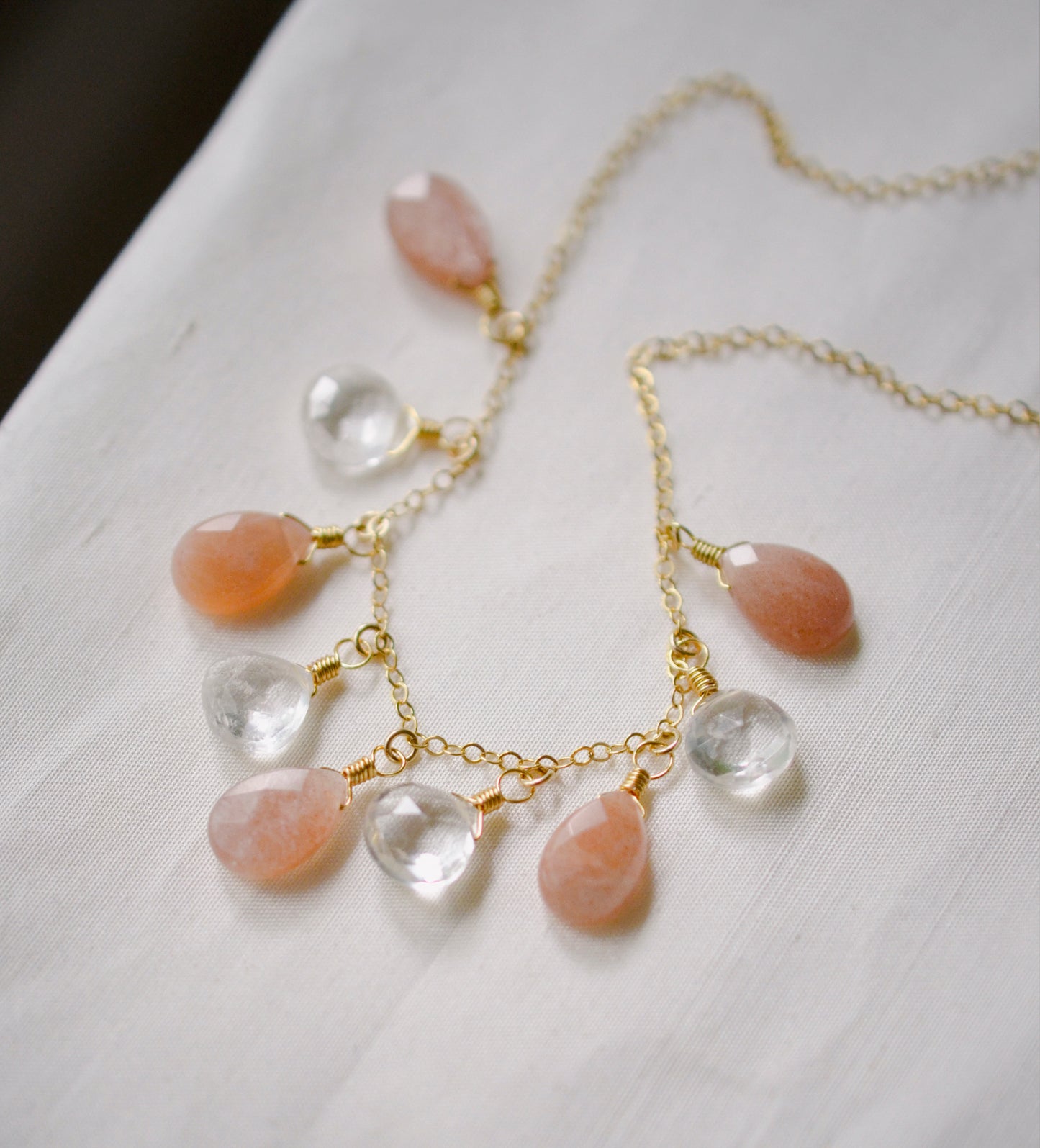 Orange, peach Sunstone and clear Crystal Quartz teardrops dangle off a 14k gold filled chain. 