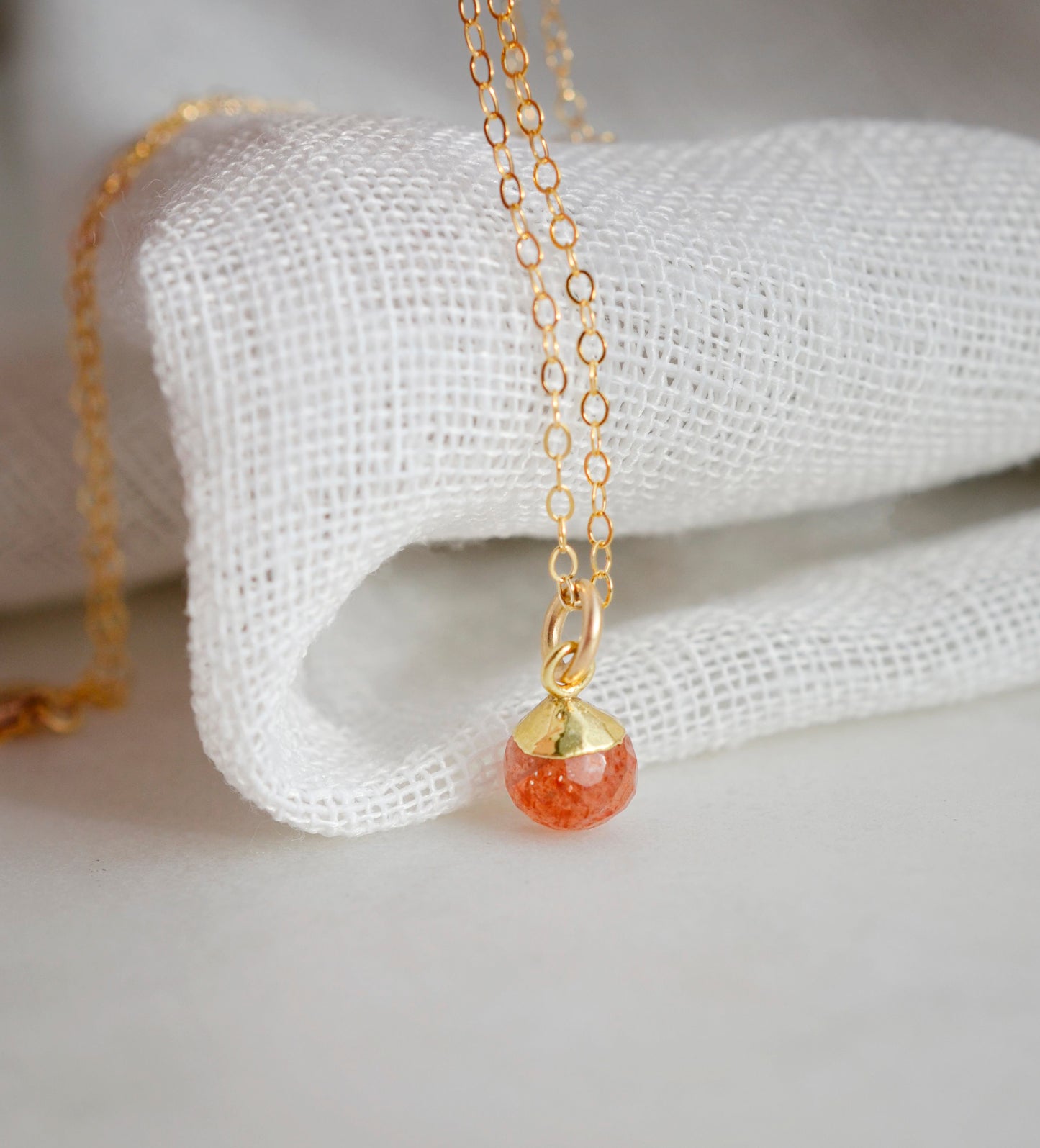 Natural orange Sunstone necklace. The stone is a faceted round and set onto a 14k gold filled chain.