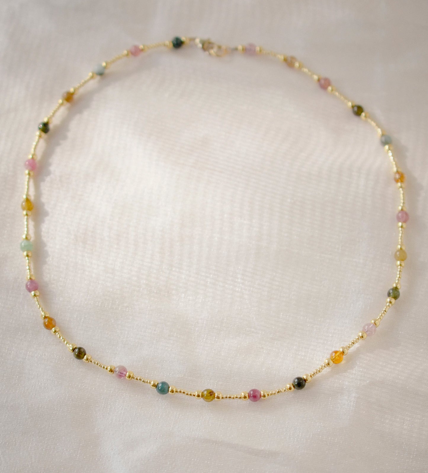Multicolored, smooth polished Tourmaline gems hand-beaded with gold plated glass beads. Colors range from pink, green, brown, yellow, or black.