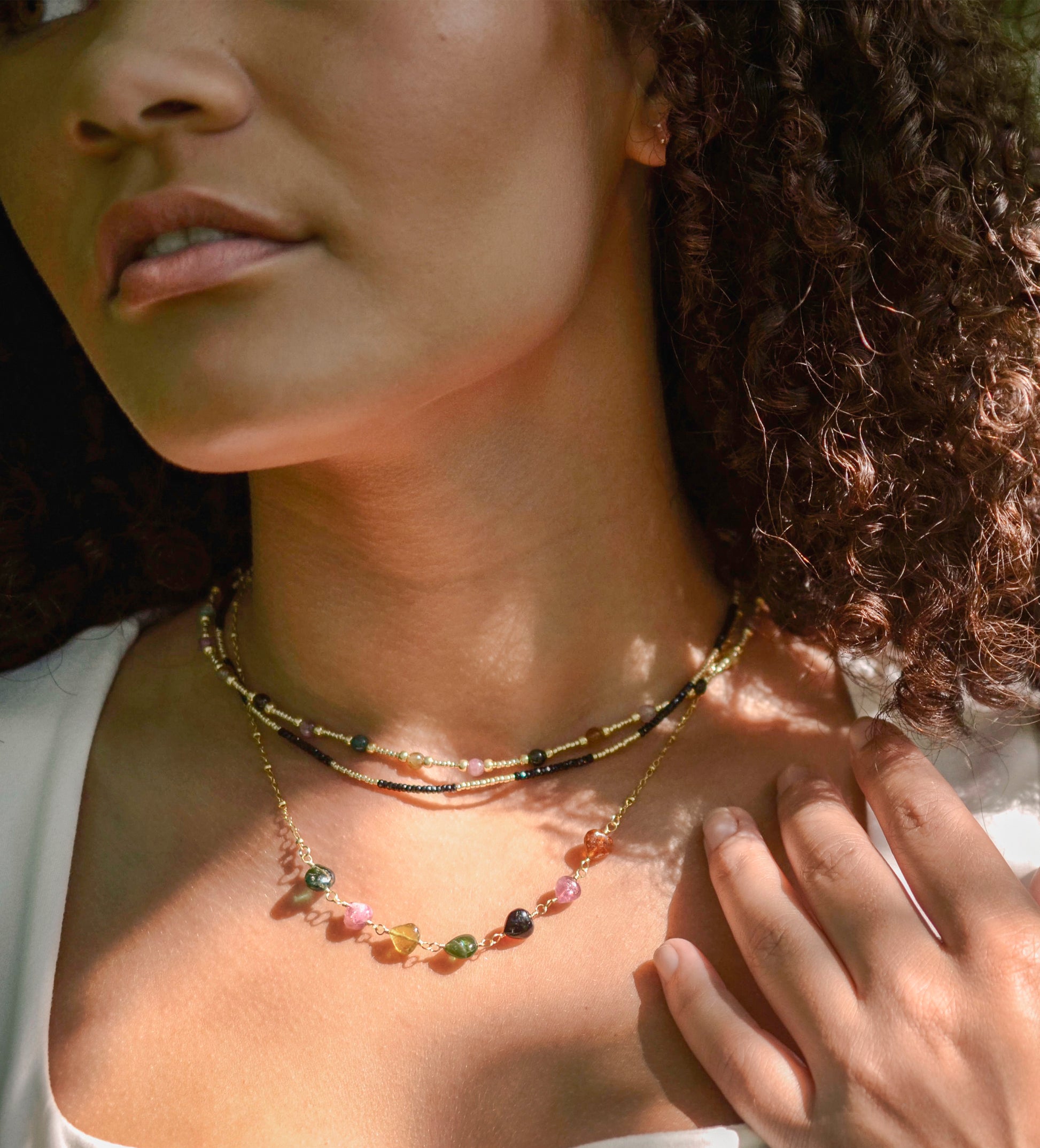 Multicolored, smooth polished Tourmaline gems hand-beaded with gold plated glass beads. Colors range from pink, green, brown, yellow, or black. Modeled image.