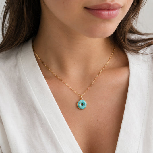 A woman wearing a round, circle doughnut shaped necklace made out of turquoise and set on a 14k gold filled dainty cable chain. All jewelry is handmade by Gemnia in Connecticut.
