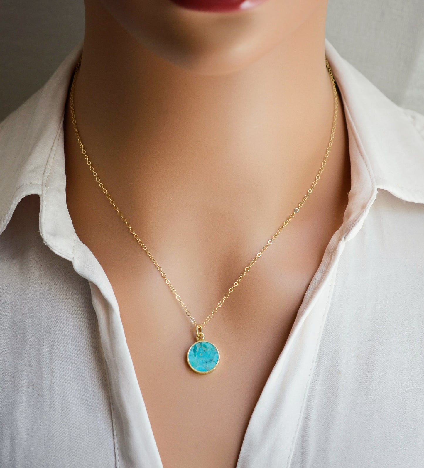 Round aqua blue Turquoise set into a gold bezel and suspended from a 14k gold filled chain. Modeled image.