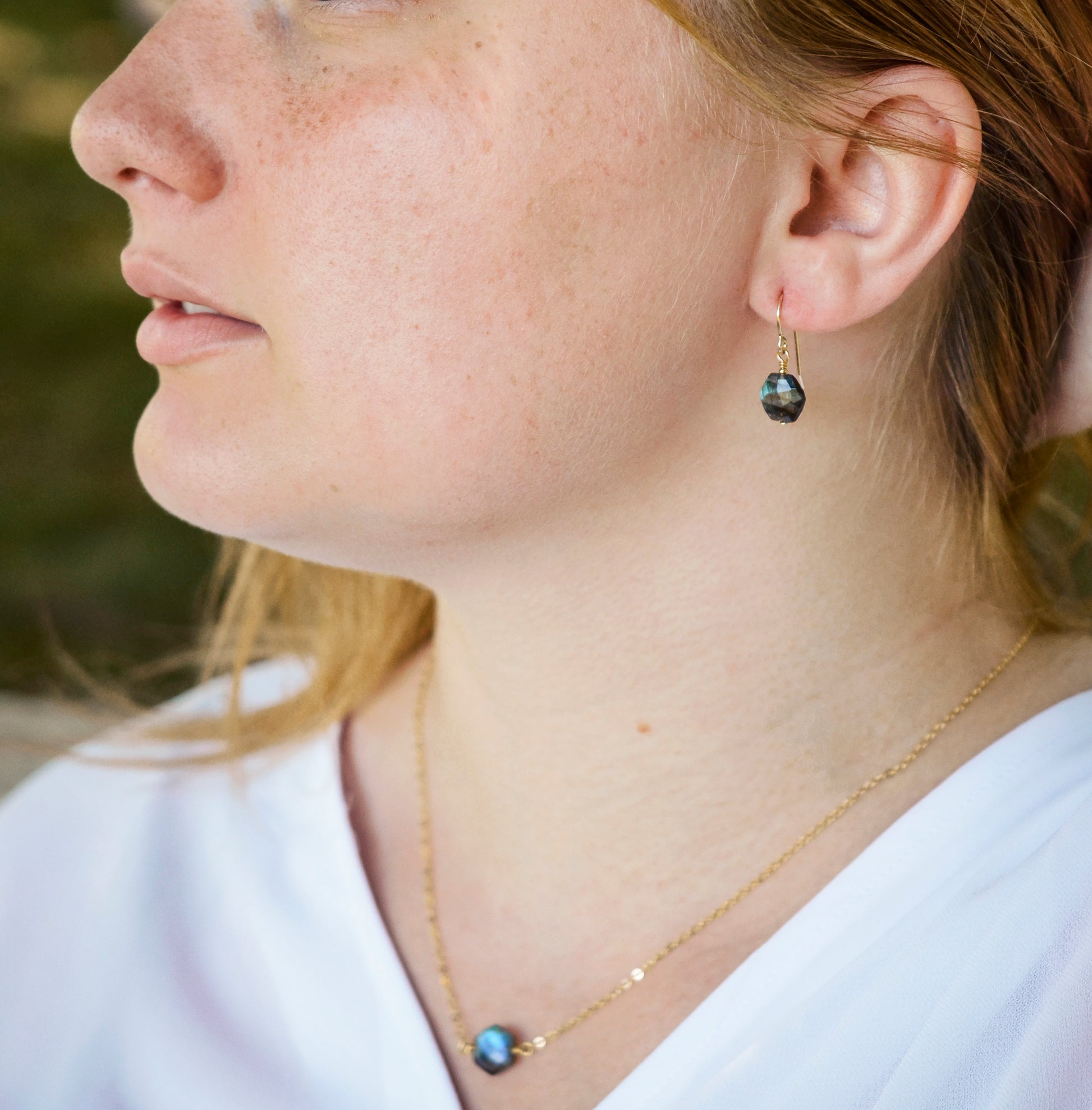 Blue flashing Labradorite gemstones in a faceted hexagonal shape dangle from 14k gold filled earring hooks. Small gold beads accent below the stone. Also available in sterling silver. Modeled image. Shown with matching necklace.