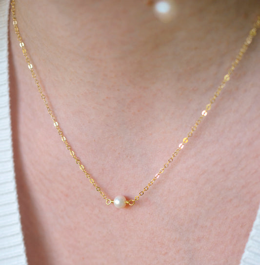 Single round white freshwater pearl necklace on a 14k gold filled chain. Modeled image. 