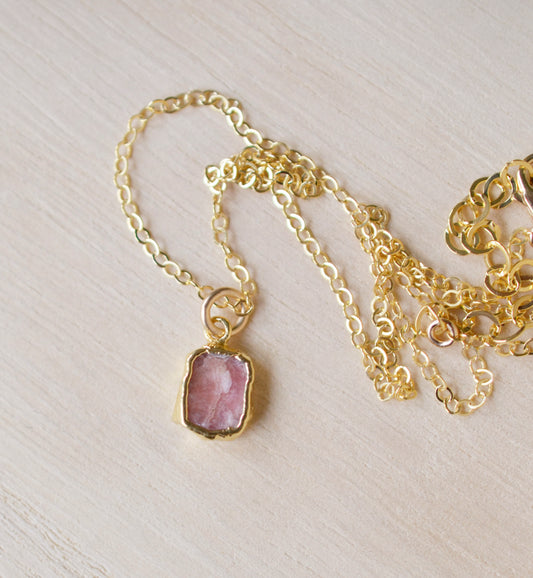 Pale pink Rhodochrosite smooth polished slice set in gold. Shown on a gold chain.