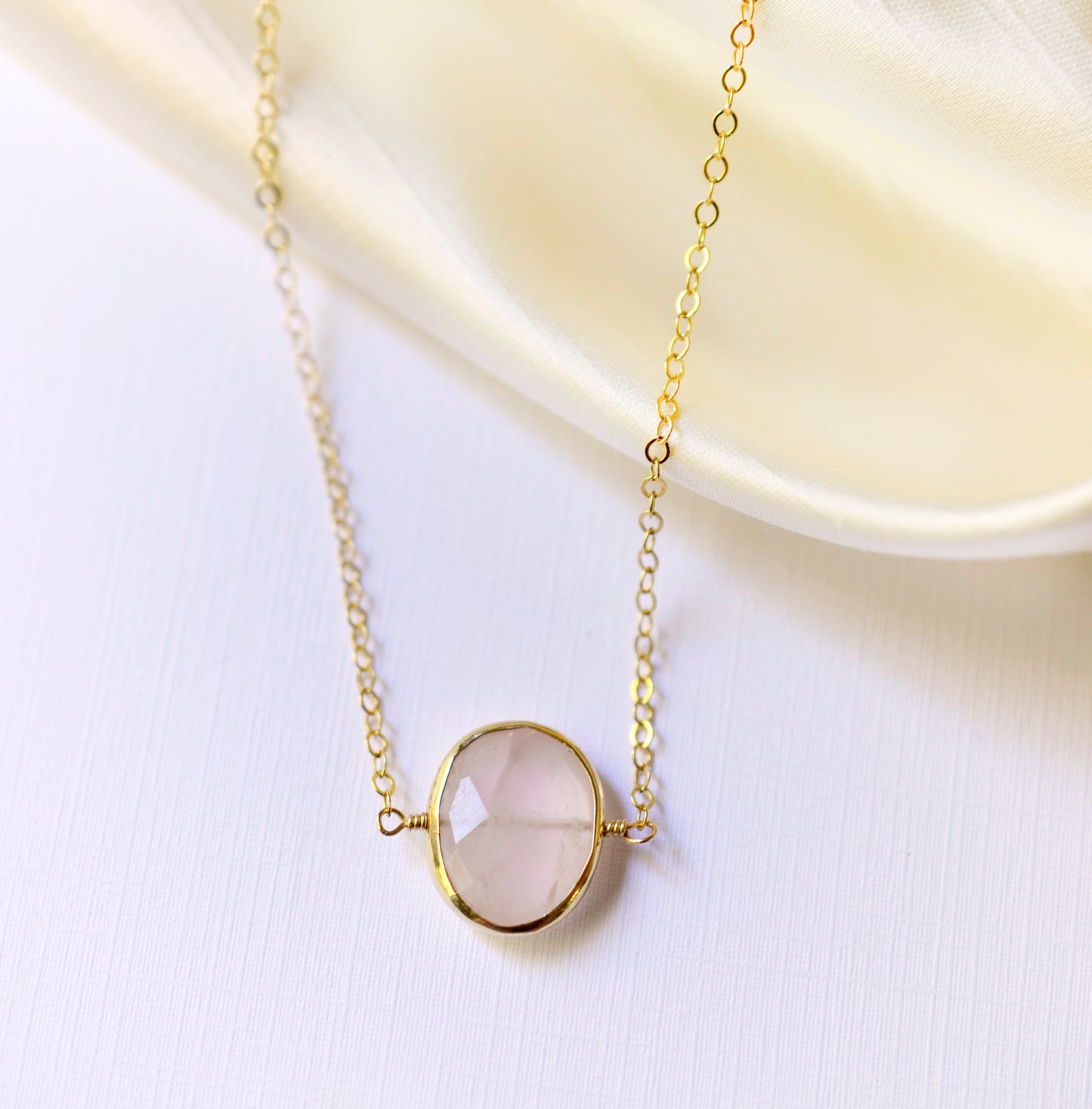 Delicate pink Rose Quartz oval coin shaped pendant with gold bezel. Chain is 14k Gold Filled.